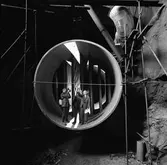 CVA, interiör från berget. Ljuddämparen för motorprovning monteras.
En man berättar, en lyssnar och en filmar.