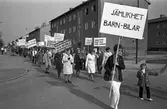 Demonstration på första maj. Människor demonstrerar och bär plakat. 
Plakatet med texten 