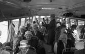 De Handikappades Riksförbund är på utflykt. Bussen är nästan fullsatt. En kvinna står i mittgången och spelar gitarr. Flera passagerare bär hatt.
DHR
