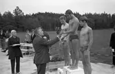 Prisutdelning i samband med invigningen av Ekbacksbadet. Tre grabbar på prispallen. Nils Brodin överlämnar en blombukett.