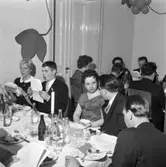 Elektrikerförbundets Arbogaavdelning har jubileumsfest. Män och kvinnor vid dukade bord. Köttbullar och potatis på tallrikarna. 