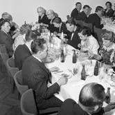 Elektrikerförbundets Arbogaavdelning har jubileumsfest. Män och kvinnor sitter till bords. Borden är dukade med ljusstakar och nejlikor i vas. Närmast kameran ses hjässan på Gustav Danielsson. På samma bordssida, bortanför kvinnan i prickig klänning, sitter Gillis Lundberg. Vid bordet bakom sitter tre unga män på rad. Stig-Arne Pettersson sitter längst till vänster.