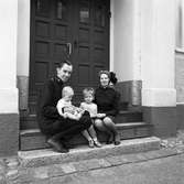 Frälsningsarméns officerare
Man och hustru med två små barn, sitter på trappan till Frälsningsarméns kyrka