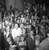 Publikbild av barn och ungdomar som samlats på Stora torget för att få en skymt att kung Gustaf Vl Adolf som är på Eriksgata i Arboga. 6000 personer har samlats för att lyssna på konungen.
För värdskapet svarade stadsfullmäktiges ordförande Jonas Carlsson och kommunalborgmästare Danliel Ekelund. Den organisationskommitté som ansvarade för arrangemangen, hade hos drätselkammaren begärt en summa av 3000 kronor för att täcka kostnaderna vid kungabesöket. Beloppet beviljades. 
Tiden för kungens besök var beräknad till 130 minuter.