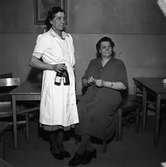 Erika Askroth och Jenny Christiansson på ölhallen på Rådhusbaren. En kvinna med ölflaskor i handen och en kvinna som sitter och stickar.