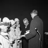 Luciakröning av stadsfullmäktiges ordförande, Jonas Carlsson.
Lucia och tre tärnor, iklädda vinterjackor. Tärnorna har pälsmössor.