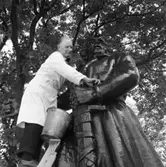 Kyrkvaktmästare Paul Eklund rengör Engelbrektsstatyn.
Han står på en stege och har en borste och en hink med vatten till hjälp.