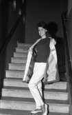 Öhrman & Melander har modevisning. Här är det Gunilla Strindler som visar upp sig för fotografen. Hon bär jumper och långbyxor med slits samt en lätt jacka. Bilden är tagen i en trappa.