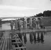 Fritidsstyrelsen alternativt Park-och idrottsstyrelsen, inspekterar Villagatsbadet.
Män i överrockar och hattar. De står på en brygga i Arbogaån. I bakgrunden ses Västerbron.
Från vänster: Evert Kjellberg, Olle Pettersson (