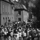 I Arboga firas 550-årsminnet av Sveriges första riksdag. Kungaparet, statsministern och ett stort antal riksdagspolitiker anländer till Arboga. Drottningen har klivit ur bilen på Rådhusgatan. Pressen är samlad. Poliser, till fots och på motorcykel, håller ordning på allmänheten. Medlemmar i Blåsorkestern, med sina instrument, ses till höger i folkhavet. Någon tittar ut genom ett fönster på Musicum. Heliga Trefaldighetskyrkan anas i bakgrunden.
Riksdagsjubileet 1985