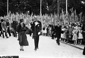 Riksdagsjubileet 1935
500-årsminnet av Sveriges första riksdag.
Kronprinsessan Louise och kung Gustaf V följda av uniformsklädda medlemmar ur hovet. Till höger går borgmästare Wilhelm Wester. Skolbarn med flaggor kantar vägen.
Repro för jubileumskatalog