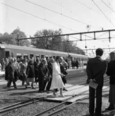 Riksdagsjubileet 1985
I Arboga firas 550-årsminnet av Sveriges första riksdag. Här har politiker från riksdagen just anlänt med tåg.
Först, i ljus dräkt, går Elsy Harrysson. Bakom henne kommer Karl-Erik Eriksson (som under året avancerade från 3:e till 2:e vice talman). Ett par rader bakom honom, kommer Mats Hellström (utrikeshandelsminister) med portfölj i handen. 
Bland de sista, på perrongen, är Gunnar Sträng (tidigare finansminister).