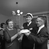 Lars-Göran Rådström har klarat studenten! (Han tillhörde sista kullen med muntliga förhör). Mamma Karin och pappa Egon håller i tårtan.
Bakom dem skymtar Hans Grönkvist, i studentmössa, samt Lars-Görans storasyster Mona-Lisa Bergström och  hennes som Thomas Bergström.