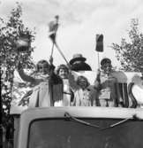 Söndagsskolans Dag med utflykt. Tre flickor och en pojke står på ett lastbilsflak och viftar med var sin svensk flagga.