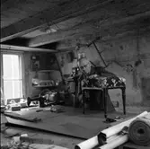 Tapetserare Fritz Lindkvist i sin verkstad i en dal av Fahlströmska gården vid Ahllöfsgatan. Fritz Lindqvist etablerade sig här 1907.
Han arbetar med en tygklädd pall som står på ett stort arbetsbord. En symaskin syns till vänster. På väggen bakom honom hänger en såg och en telefon. I taket hänger en skomakarlampa.