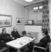 Nu finns det en TV-apparat i polisens dagrum!
Tre uniformsklädda polismän sitter vid kaffebordet och ser en polisfilm på TV. 
Från vänster: Bo Hammar, Gösta Brokvist och Jan Dovholt (med ryggen mot fotografen).
TV´n står på fönsterbrädan. Där står även en radioapparat.