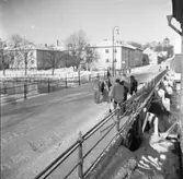 Män som samtalar på Herrgårdsbron. Två bockar är uppställda och en man bär en stege, de har arbete att utföra. Två av männen bär storvästar. Några andra har krimmelmössor. Två personer cyklar. En kvinna i päls är på väg över bron.
Herrgårdsvägen, riktning Sankt Nikolai kyrka/ Nicolai kyrka. Fastigheter vid Strandvägen. Till höger anas magasinet tillhörande Arboga Kvarn och Maltfabrik.
Två av männen bär storvästar. Några andra har krimmelmössor. Det är vinter och snö.
Det är vinter och snö.