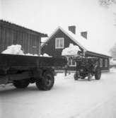 Snöröjning på Storgatan. En traktor med skopa lastar snö på en kärra.