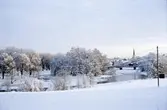 Vintervy över staden, sedd från Törnberget. Is på Arbogaån. Strömsnäsbron och Heliga Trefaldighetskyrkan. Snötäckt landskap.