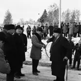 Bandet klipps. Örebrovägen öppnas efter ombyggnad. En stor publik, de flesta män, har samlats. 
Det är vinter och snö.