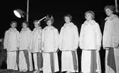 Sång efter Luciakröningen på Stora torget.
Från vänster: Iréne Johansson, Margareta Norman, Christina Hedqvist, Britt-Marie Gustavsson (Lucia), Hjördis Holmqvist, Monika Norén och Gerd Eklöf.
Flickorna har varma vinterjackor på sig.