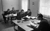 Försvarets Materielverks datorenheten i lokaler i Arboga Margarinfabriks kontor vid Nygatan.
Arne Jigelius, till höger, är chef för enheten.
Fem män vid arbetsbord. De jobbar med pärmar och papper. På borden finns askkoppar.
FMV, CVA, Centrala Verkstaden Arboga
