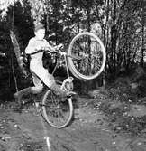 Cykelcross är en ny sportfluga för ungdomar. Här kommer Nils Karlsson, tävlande för Arbogas Kronorna. Laget möter Rövarna från Fellingsbro som tävlar på hemmaplan.
Banan är 450 meter lång.
Den här bilden finns med i Reinhold Carlssons bok 
