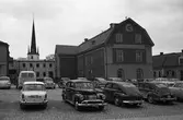 Bilar parkerade på Stora torget. Rådhuset och dess innegård ses i bakgrunden samt tornet på Heliga Trefaldighetskyrkan.
Fotografen har angivit att bilden ingår i 