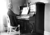 Tonsättaren Ruben Liljefors spelar piano sannolikt i hemmet, Uppsala