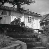 Vy från Figeholm, bostadshus med träpanel och sadeltak och trappa.