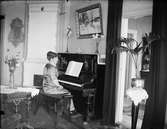 Kvinna sitter vid ett piano i bostadsmiljö, Östhammar, Uppland
