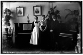Hålhults sanatorium, interiör, två män, två kvinnor, står vid ett piano och en orgel. Från vänster syster Rut Larsson, Betty Waller dr. Wallers dotter.