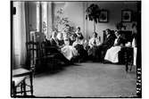 Hållahults sanatorium, interiör, gruppbild sitter runt ett litet bord vid ett piano, kaffekanna på bordet, nr tre från höger Betty Waller dr Wallers dotter.
