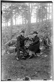 Hålahult sanatorium, exteriör, två män sitter på en bänk i skogen, klädda i kostym överrock hatt.