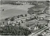 Flygfoto över Vivstavarvs arbetarbostäder, spruthuset och brädgård till höger samt herrgården till vänster. Vykort.