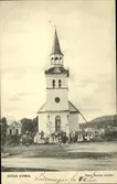 Vykort med motiv av kyrkan i Stöde med en grupp människor uppställda för fotografering utanför.
