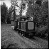 På smalspåret ses lokomotor med öppen godsvagn.