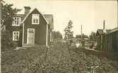 Vykort med motiv över en stuga med tillhörande potatisodling och dess ägare i Torpshammar.