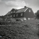 Bostadshus med träpanel, mansardtak och frontespis.