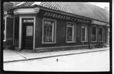 Huset uppfört efter 1823 års brand. Skyltfönster insattes 1901 men de nuvarande tillkom 1931 och 1938.  ( förslag t. bevar.)  Affären på bilden är Juvelerare C.V. Törnlöf  A T Törngrens Eftr. Nuvarande Ernst Forssell Guldsmedsaffär.