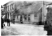 Bild 1: Foto efter 1912-07-04, då Albert Skantze fick föreläggande att anordna takrännor och stuprör.  Skyltfönster tillkom 1909 o 1910.  På skylten står N.Åkesson Skrädderiaffär.  På baksidan av org.bild 2 står det 