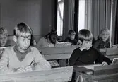 Elever födda 1955 sittandes vid sina skolbänkar i klassrummet, Kålleredsskolan 1966/67. Från vänster: (i bakgrunden) Börje Glamheden, Ove Englund och (nerböjd) Ulla Johansson. Längst till höger sitter Elisabeth Söderkvist.