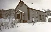 Sionkapellet vid Gamla Riksvägen, 1940-tal. Byggt mitten av 1930-talet och rivet mitten av 1970-talet. Till höger fanns två lägenheter. I bottenvåningen var Kållereds manuella telefonstation inrymd, vilken sköttes av Julia och Claes Franzén, som också bodde där. Den lades ner 1950. I källaren låg Bertil Kjellmans Fiskaffär. Tidigare mjölkaffär Jenny Lundberg.
