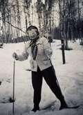 Signe Fredriksson (1901 - 1992) står på ett par skidor omgiven av snötäckt omgivning, okänd plats och årtal. Hon bodde i 