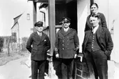 Brandsynenämnden. Tre män, var av två i uniform, och en kvinna står utanför ett hus.