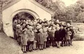 Söndagsskolebarn står utanför Kållereds kyrka omkring 1940 - 1945. Där står bland annat lärarinnan 