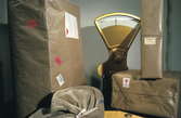 Seriebild H 13a. Paketvåg omgiven av paket med olika etiketter: 
