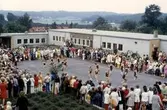 Examen och skolavslutning för elever på inre skolgården vid Brattåsskolan cirka 1970. Några elever gör en dansuppvisning. Vommedalsområdet (rött tegel) och Heljered ses i bakgrunden.
Relaterat motiv: A1518.