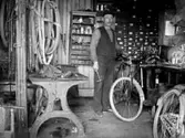 EN CYKELREPARATÖR I SIN VERKSTAD.