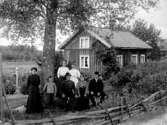 SLÄKTGRUPP SAMLAD I TRÄDGÅRDEN FRAMFÖR SITT BOSTADSHUS.